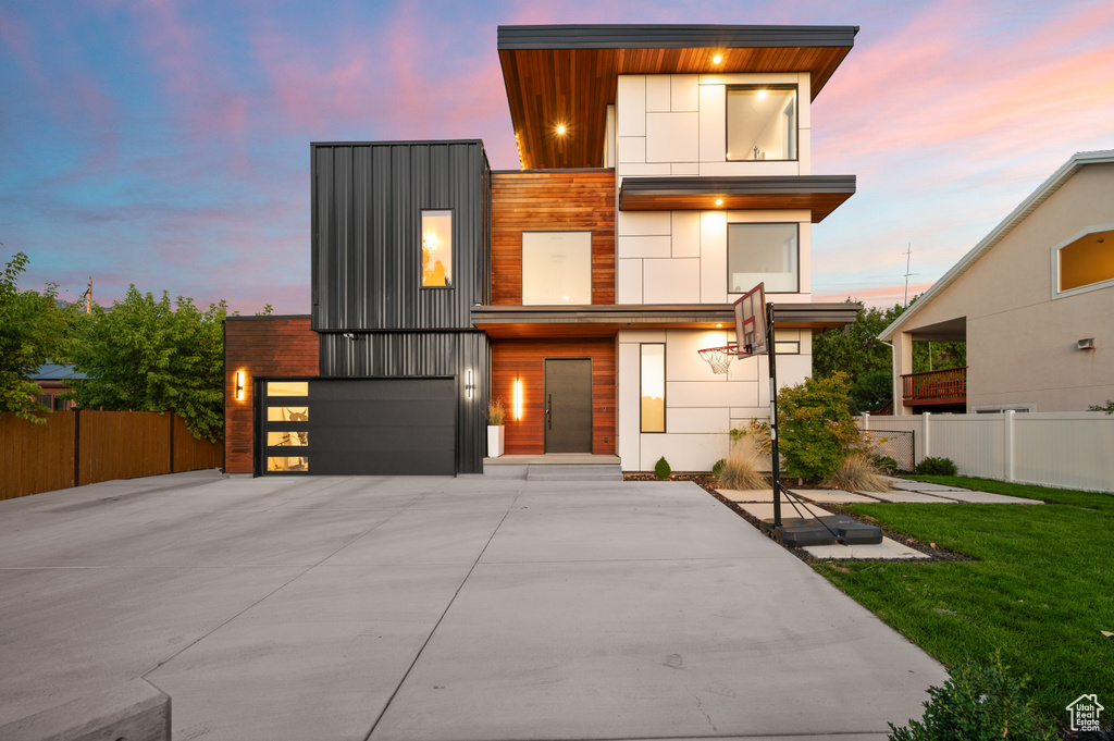 Modern home with a garage, fence, driveway, and a front yard