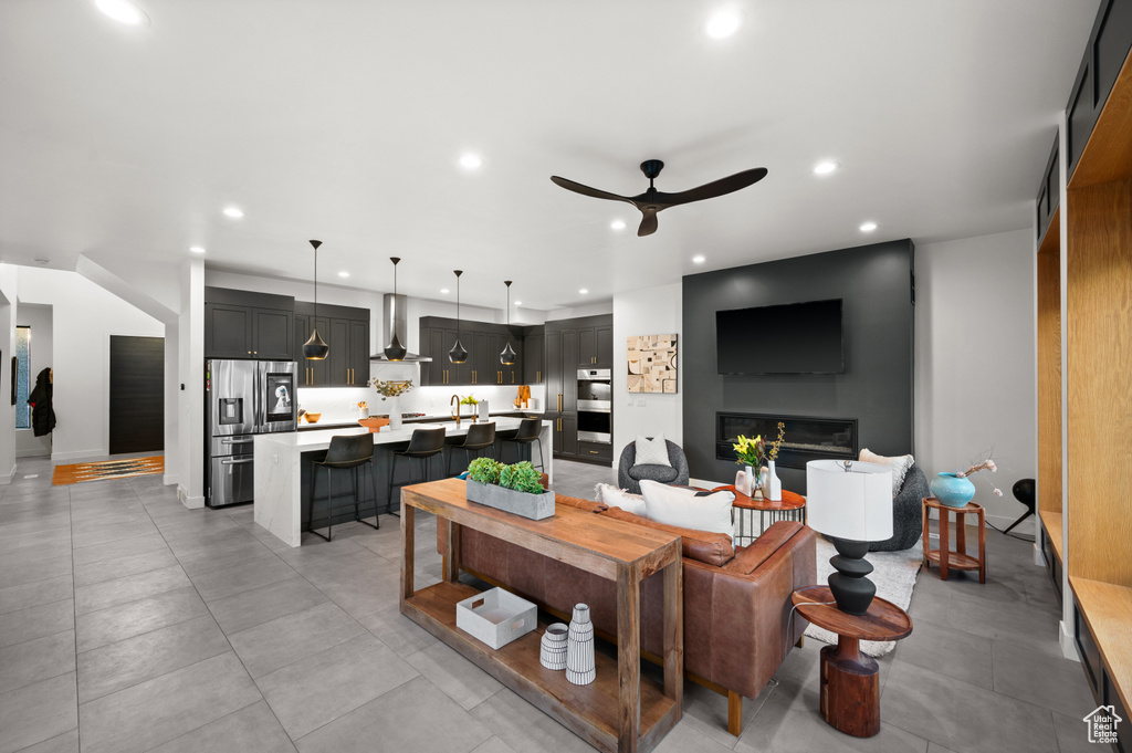 Living room with a glass covered fireplace, a ceiling fan, and recessed lighting
