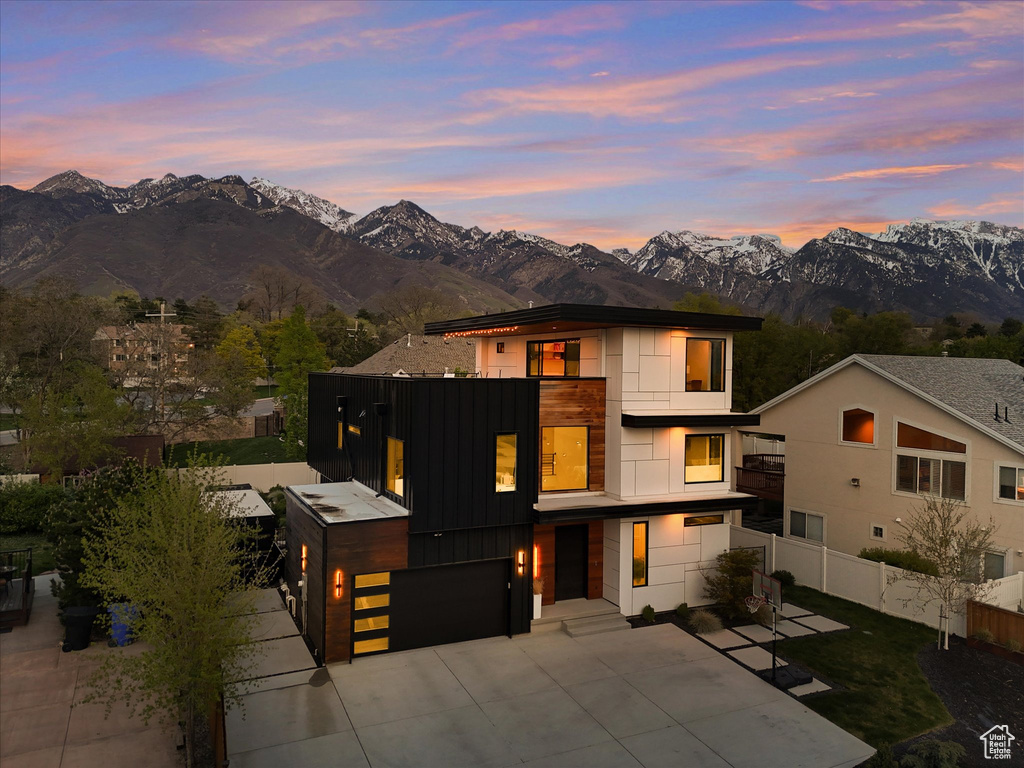 Contemporary house with concrete driveway, board and batten siding, a mountain view, fence, and a garage