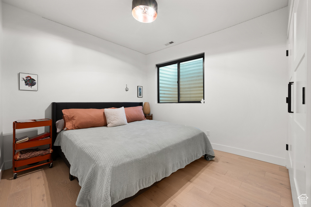 Bedroom with baseboards, visible vents, and wood finished floors