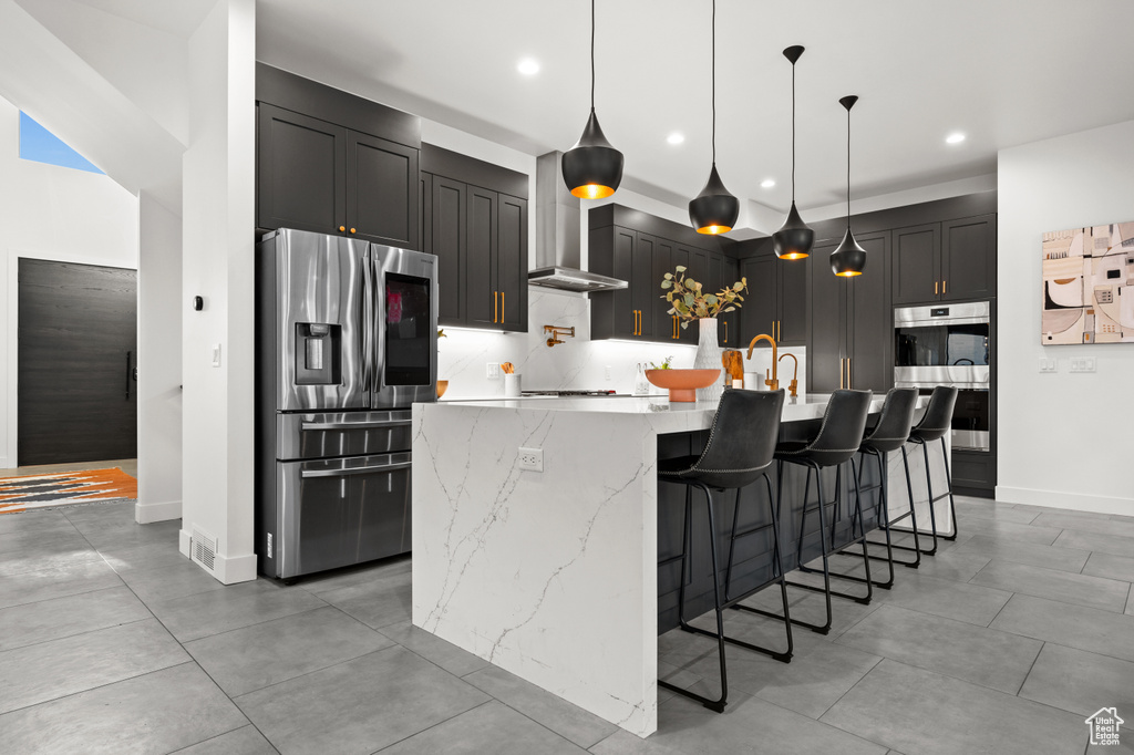 Kitchen with appliances with stainless steel finishes, light stone counters, recessed lighting, and a large island