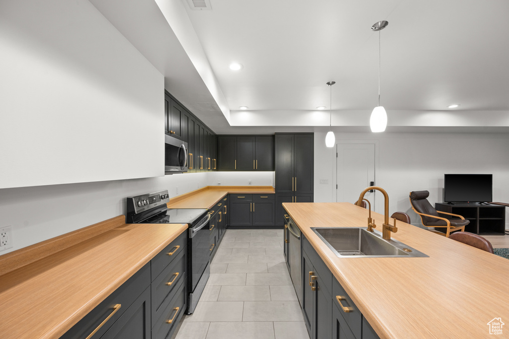 Kitchen with light tile patterned floors, stainless steel appliances, light countertops, and a sink