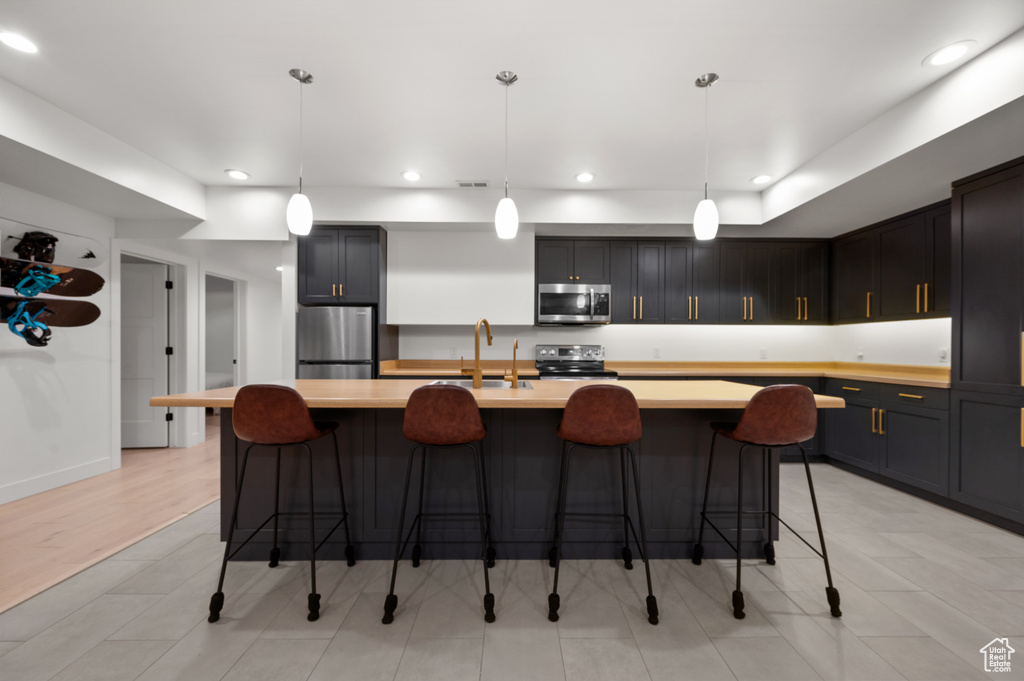 Kitchen featuring stainless steel appliances, light countertops, recessed lighting, and a sink