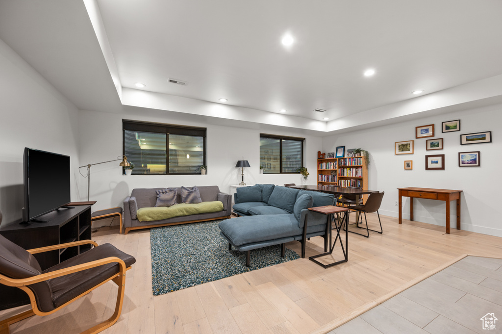 Living area featuring light wood-type flooring, recessed lighting, visible vents, and a tray ceiling