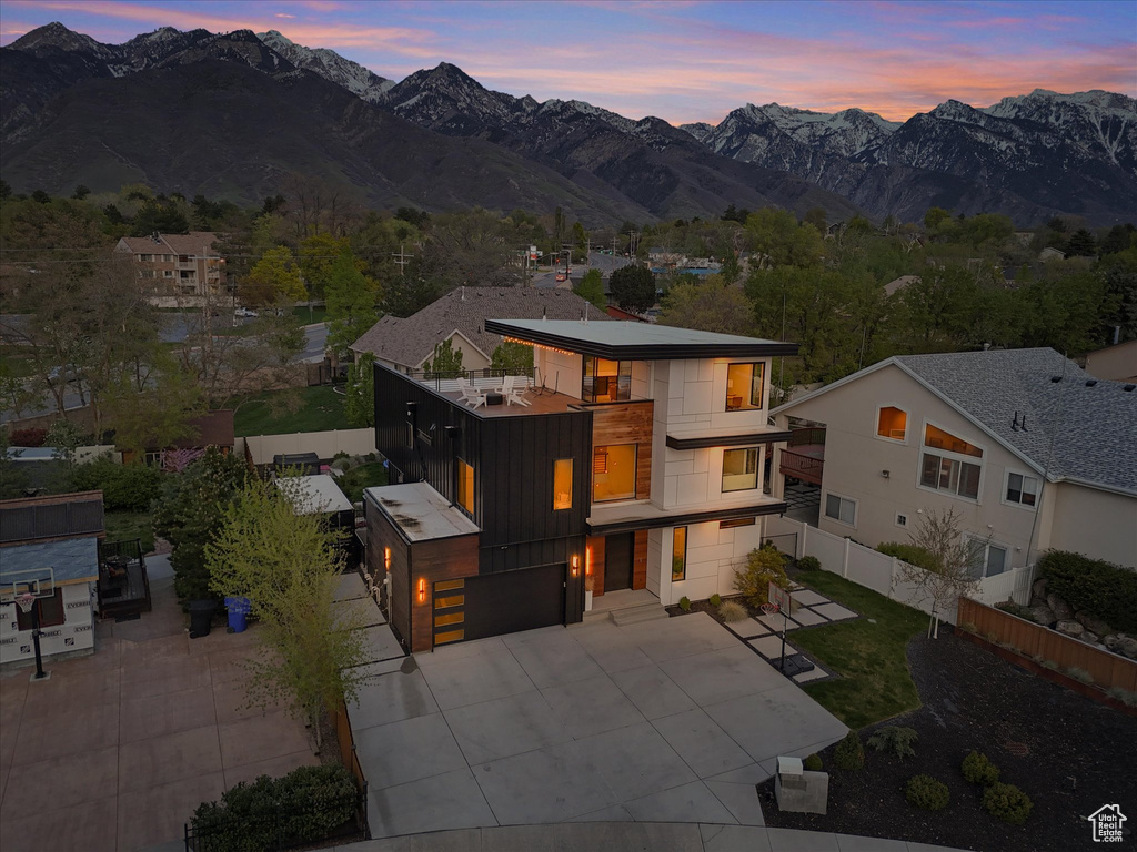View of front facade with a mountain view, fence, a garage, and a balcony