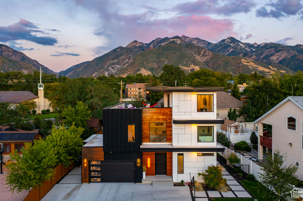 View of front of house featuring fence, a garage, a mountain view, a balcony, and concrete driveway