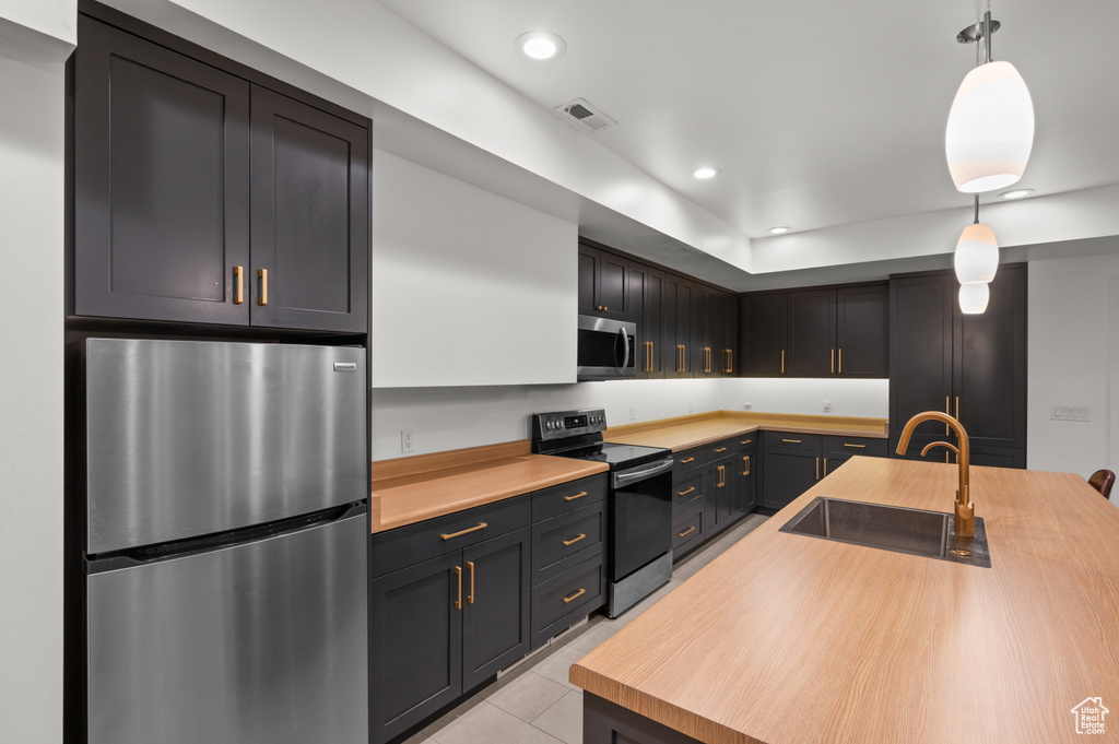 Kitchen with light tile patterned floors, a sink, appliances with stainless steel finishes, recessed lighting, and decorative light fixtures