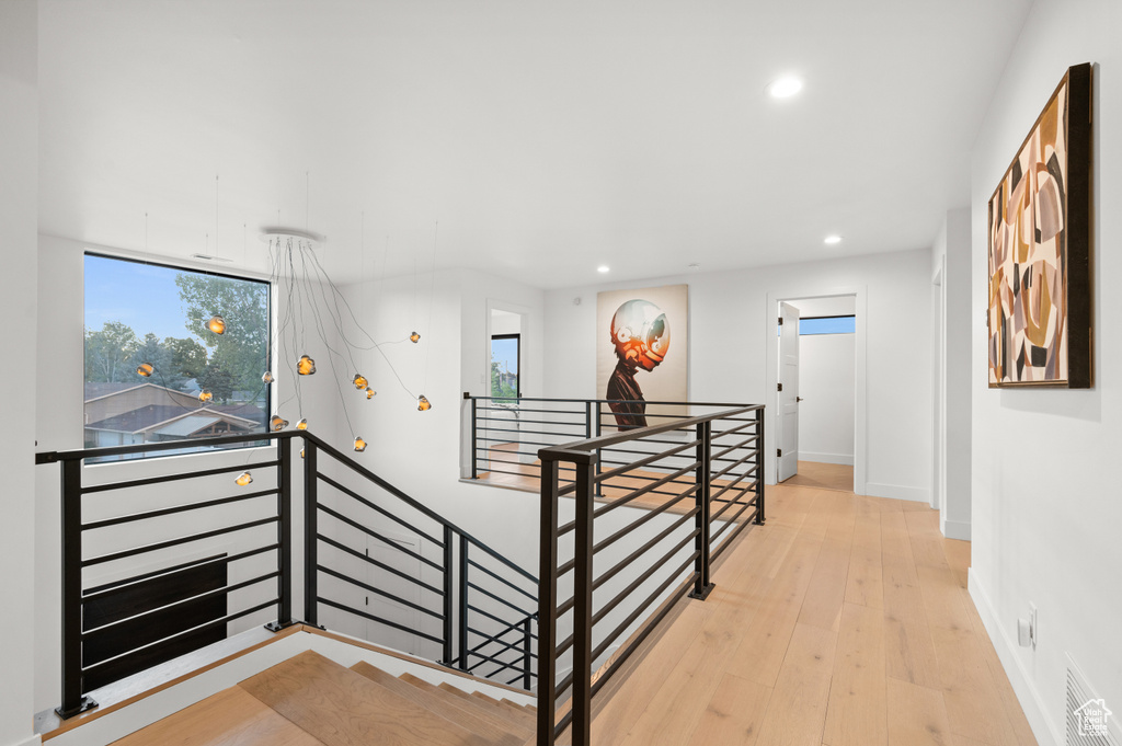 Corridor with an upstairs landing, visible vents, a healthy amount of sunlight, and recessed lighting