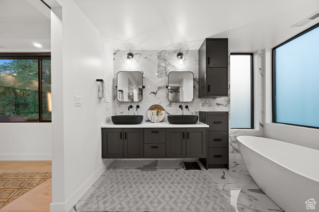 Full bathroom featuring a freestanding tub, visible vents, double vanity, and a sink