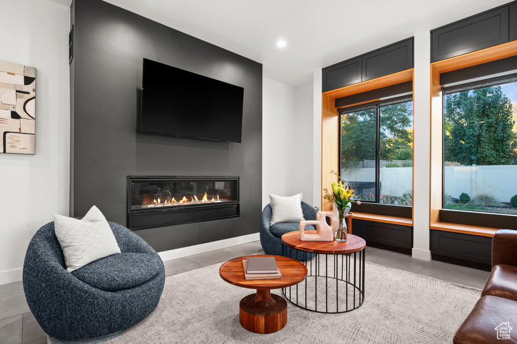 Sitting room featuring a healthy amount of sunlight, baseboards, and a glass covered fireplace