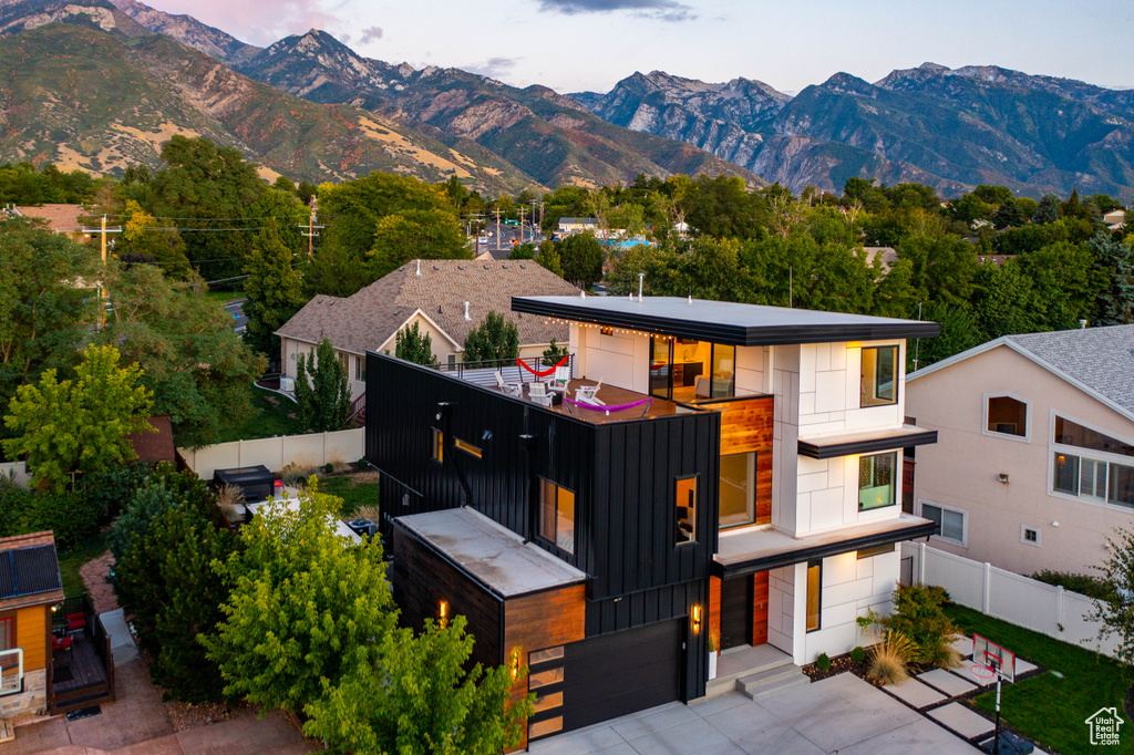 Contemporary home featuring a garage, a mountain view, fence, and board and batten siding
