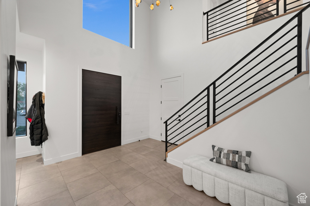 Entryway with a towering ceiling, baseboards, light tile patterned floors, and stairs