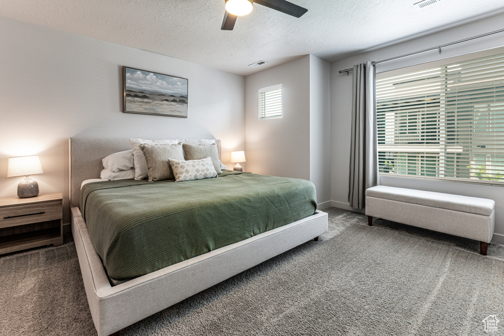 Bedroom featuring carpet floors, a textured ceiling, baseboards, and ceiling fan