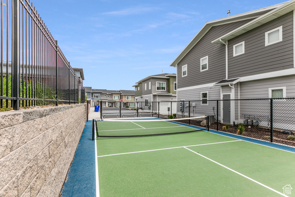 View of tennis court with a residential view and fence