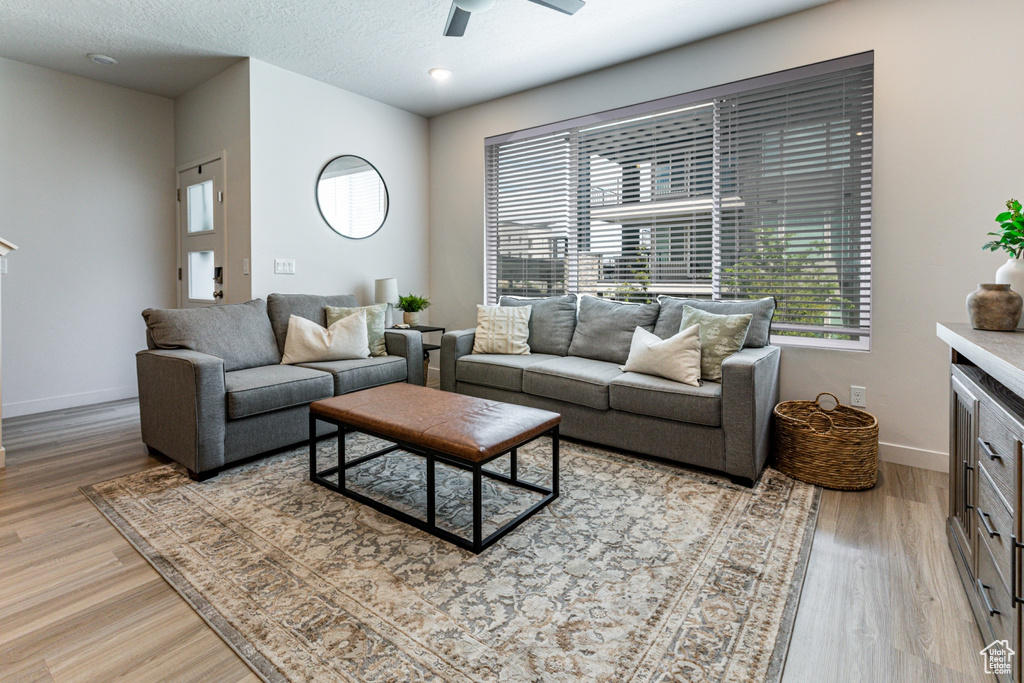 Living room with light wood-style floors, baseboards, and a ceiling fan