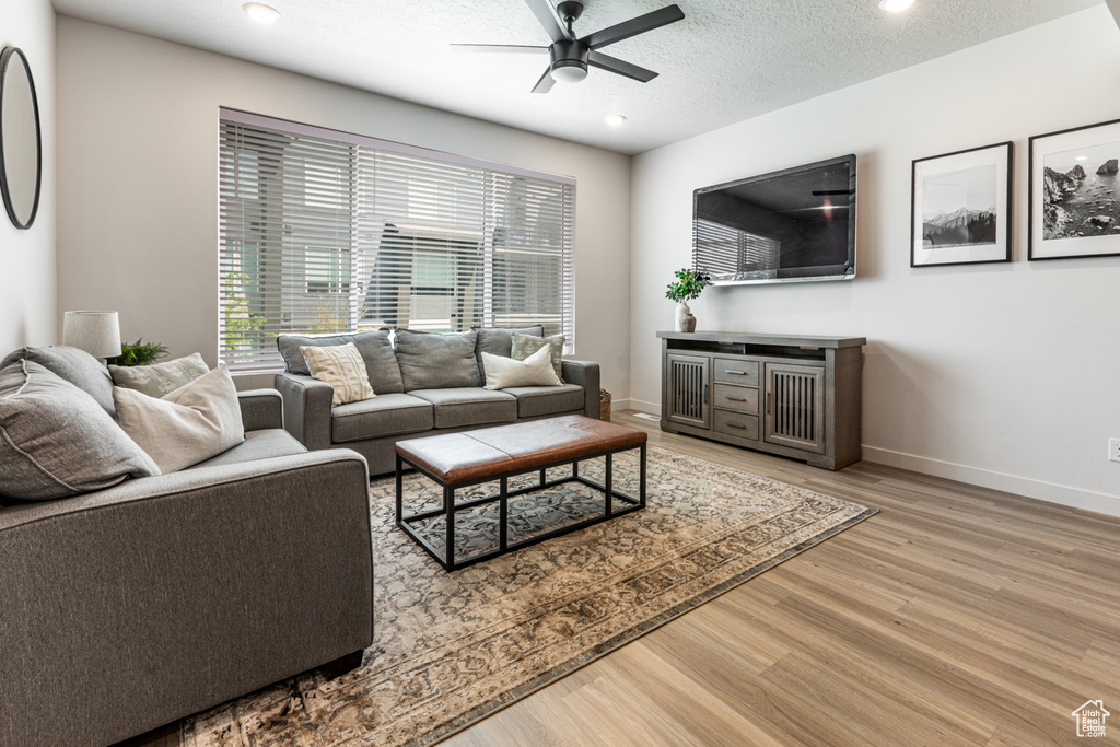 Living area featuring ceiling fan, light wood-style flooring, baseboards, recessed lighting, and a textured ceiling