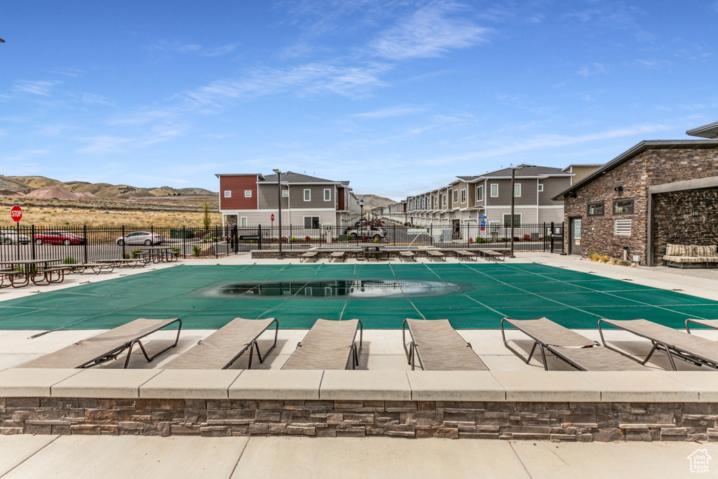 Community pool with fence, a patio area, a residential view, and a mountain view