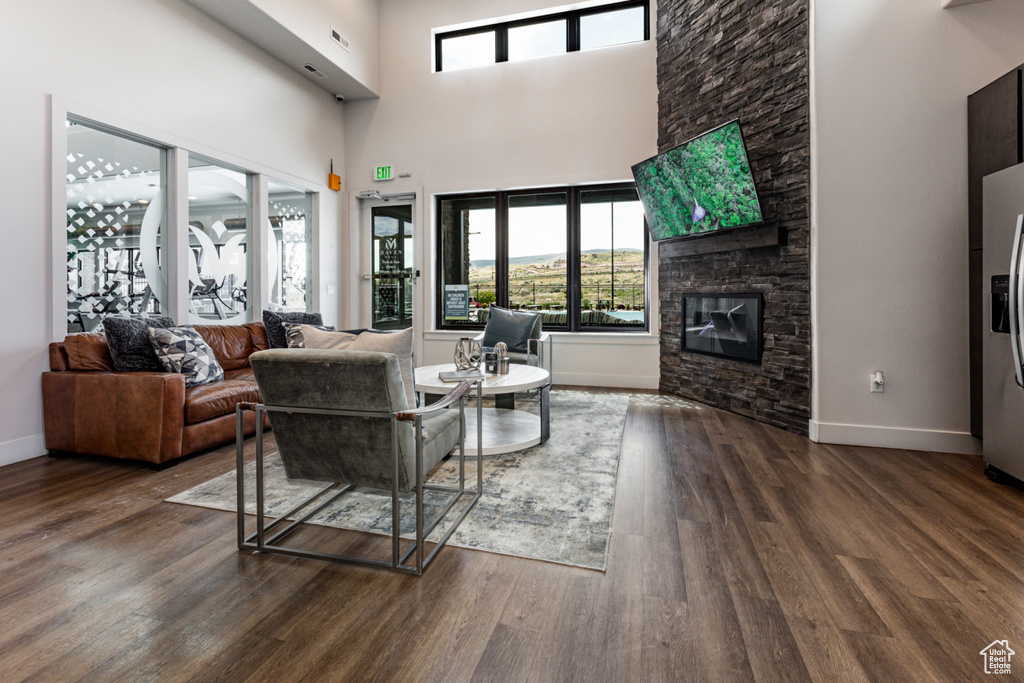 Living room with plenty of natural light, wood finished floors, baseboards, and a high ceiling