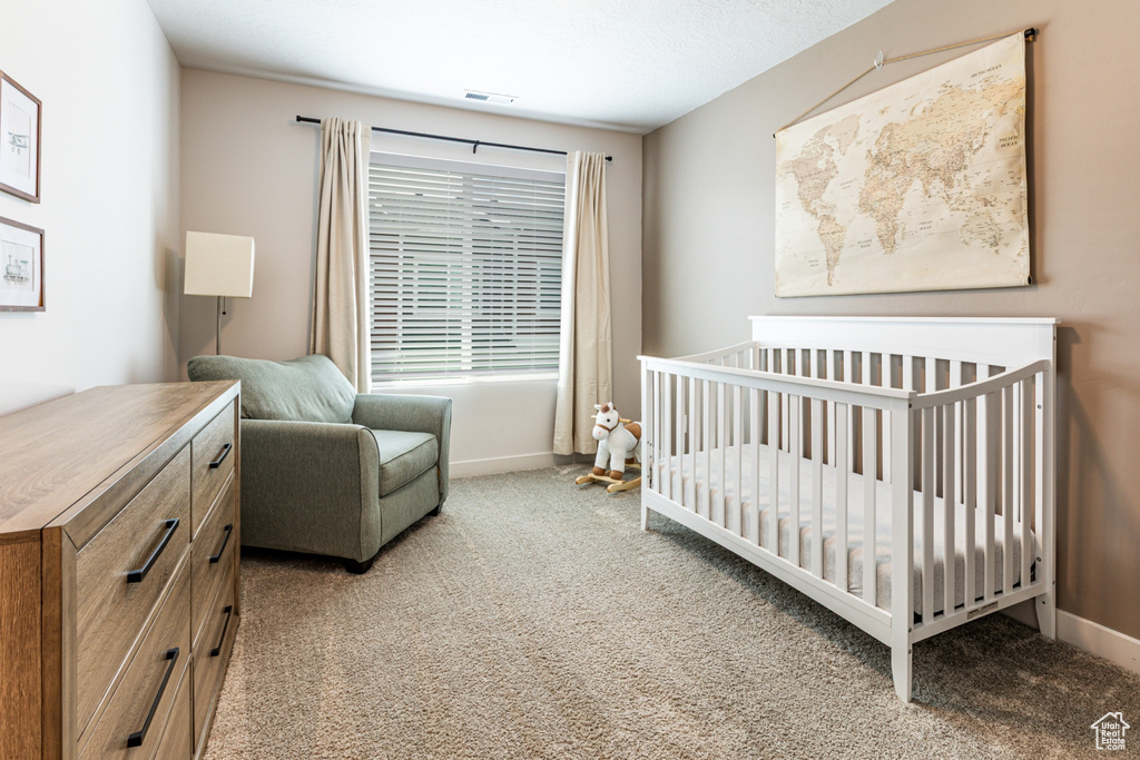 Bedroom featuring carpet, baseboards, and a nursery area
