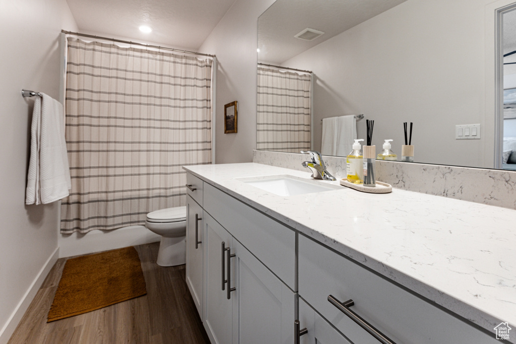 Full bathroom featuring wood finished floors, vanity, toilet, baseboards, and a shower with shower curtain