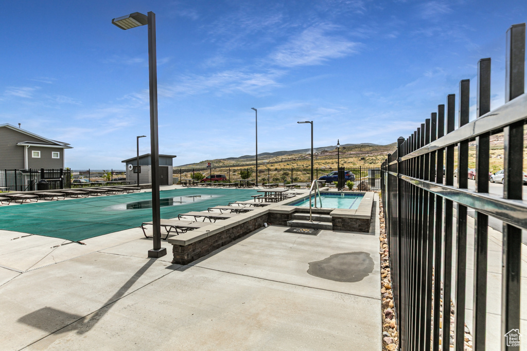Community pool with a patio, a mountain view, fence, and an outdoor structure