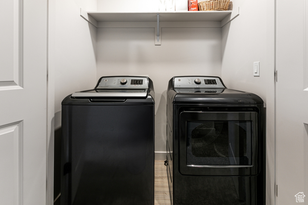Washroom with washing machine and dryer and wood finished floors