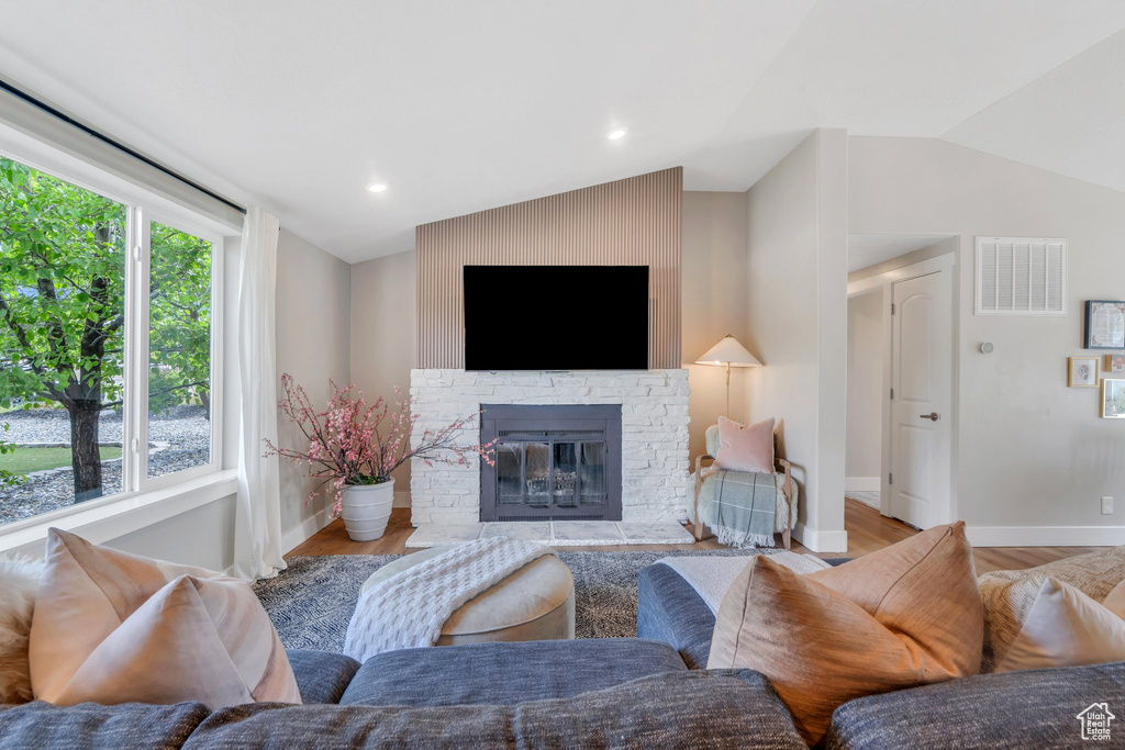 Living area featuring lofted ceiling, wood finished floors, a glass covered fireplace, baseboards, and recessed lighting