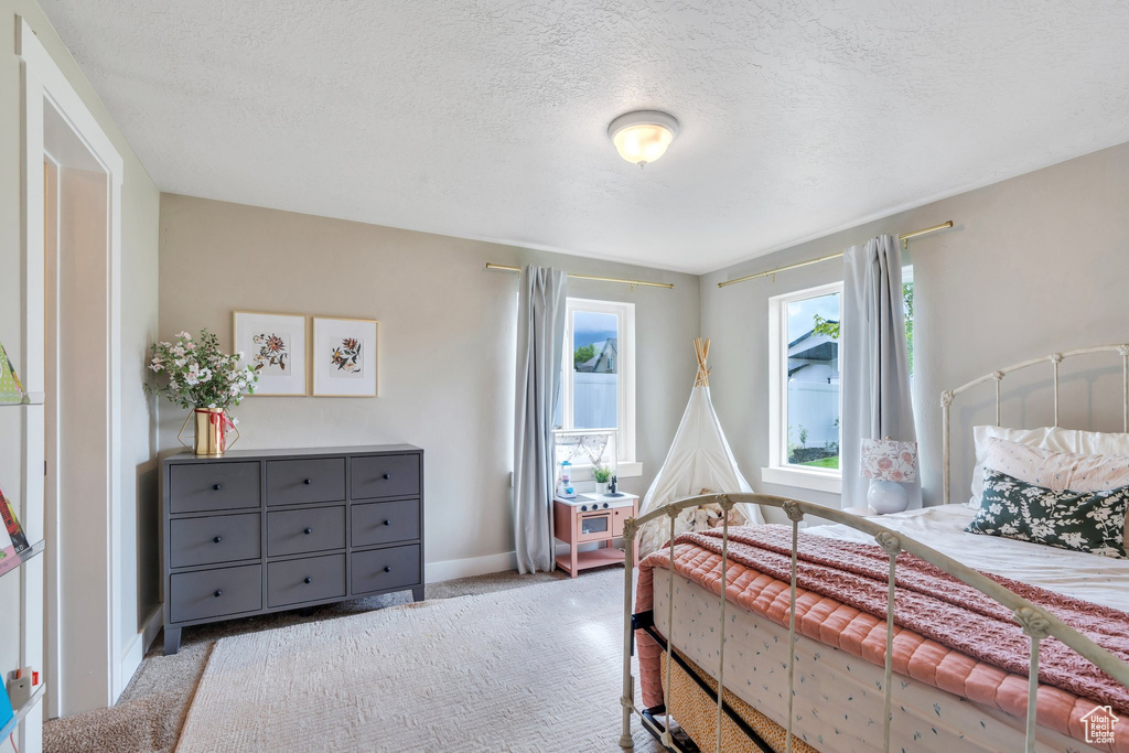 Bedroom with carpet, a textured ceiling, and baseboards