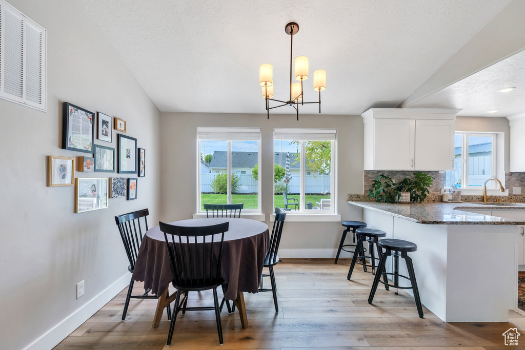 Dining area with light wood-type flooring, healthy amount of natural light, baseboards, and a chandelier