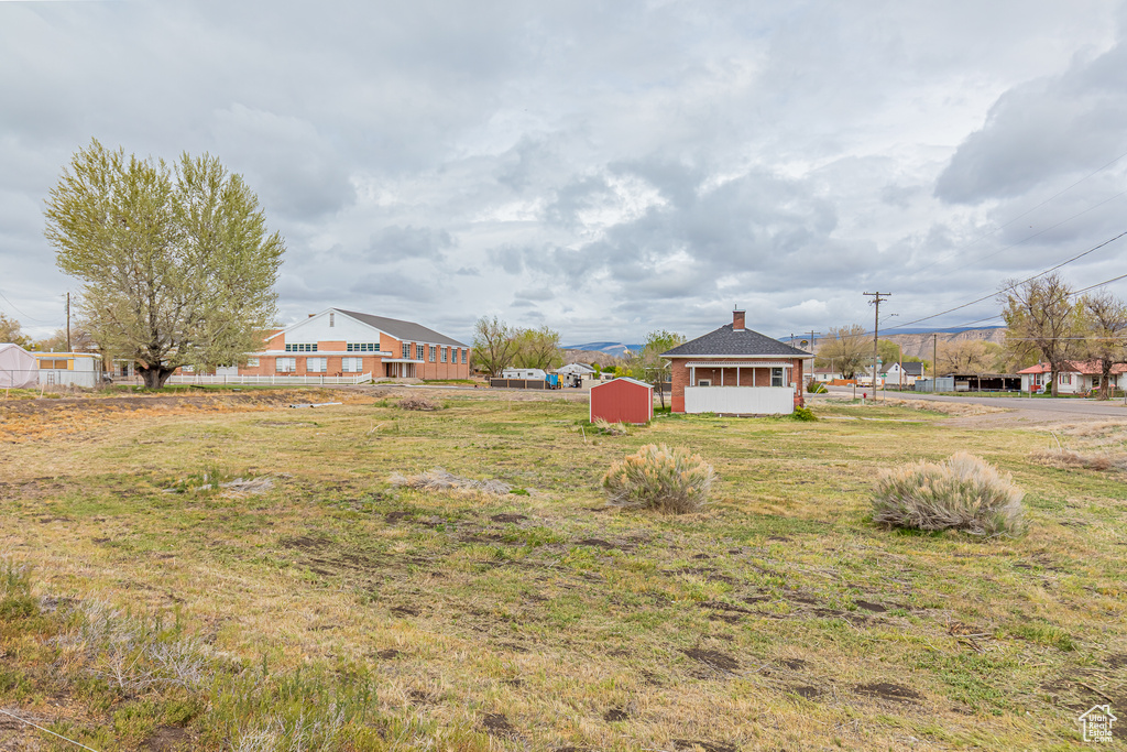 View of grassy yard featuring a storage unit and an outdoor structure