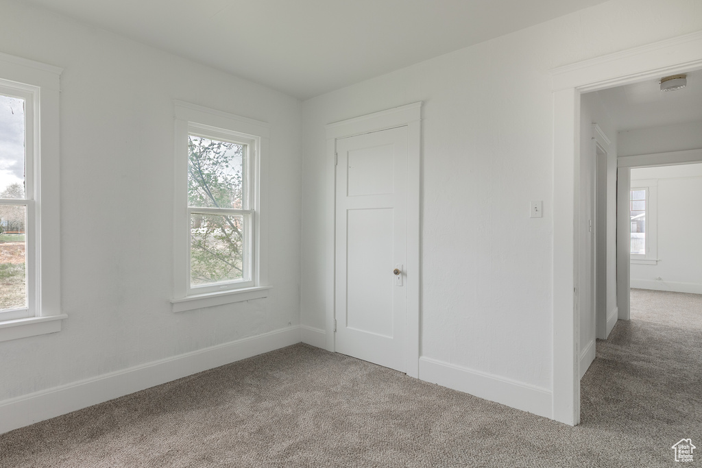 Unfurnished bedroom with carpet floors, multiple windows, and baseboards
