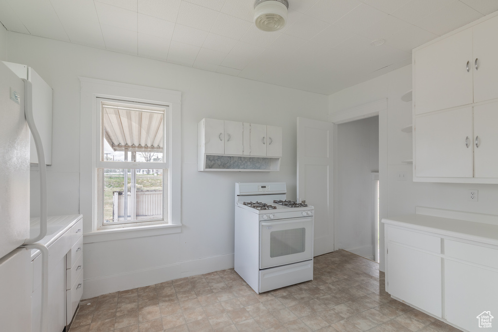 Kitchen featuring white appliances, open shelves, light countertops, white cabinets, and washer / dryer