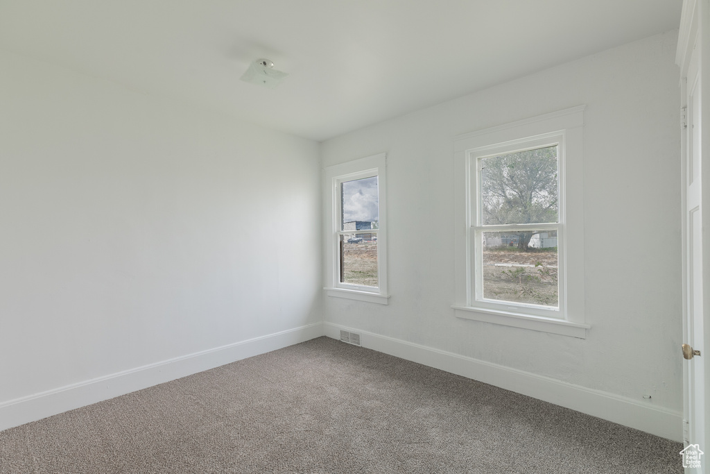 Carpeted spare room featuring healthy amount of natural light and baseboards