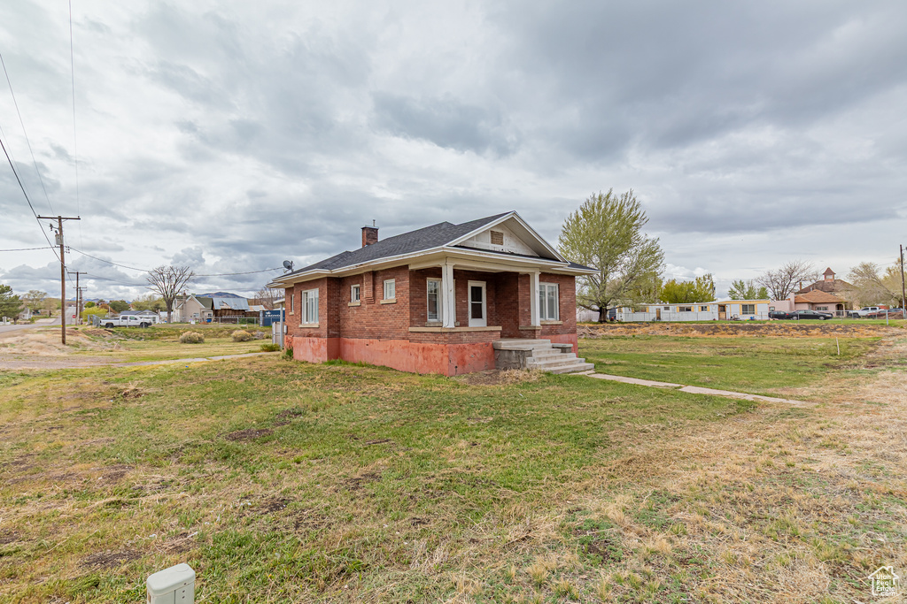 View of front of property featuring a chimney, brick siding, and a front lawn