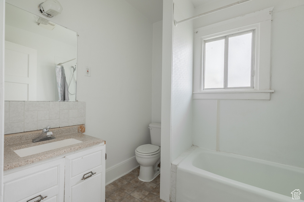 Bathroom with toilet, a shower, baseboards, vanity, and a tub