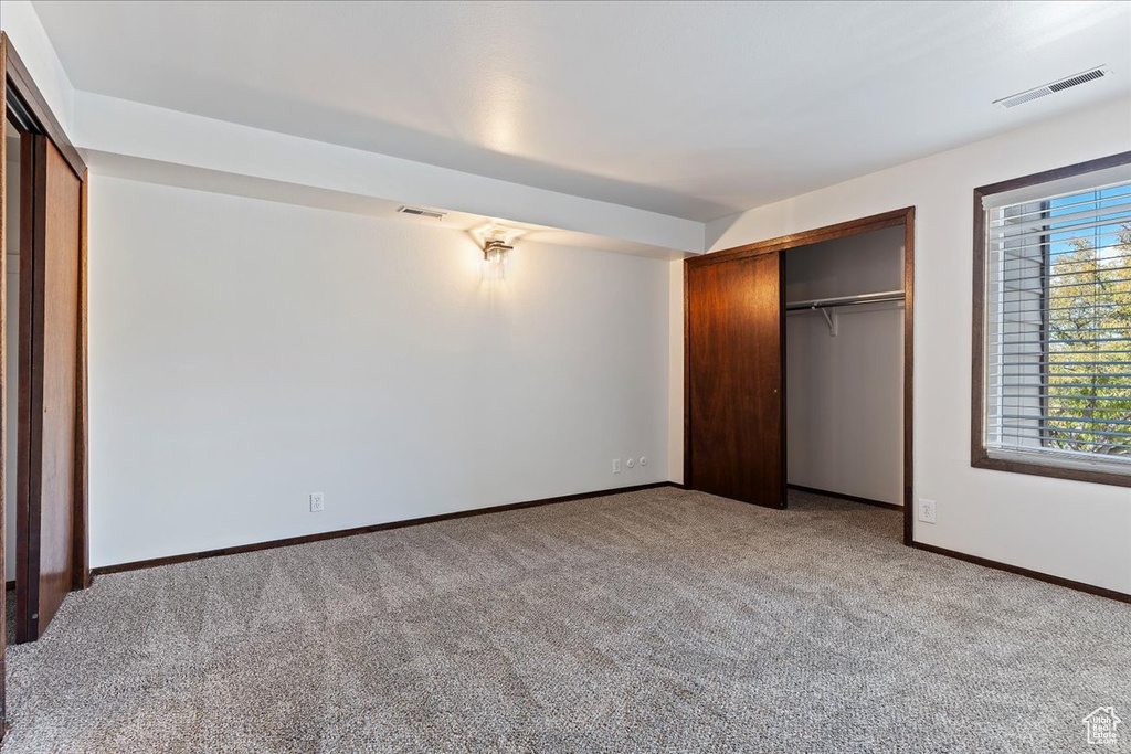 Unfurnished bedroom featuring light carpet, baseboards, and a closet