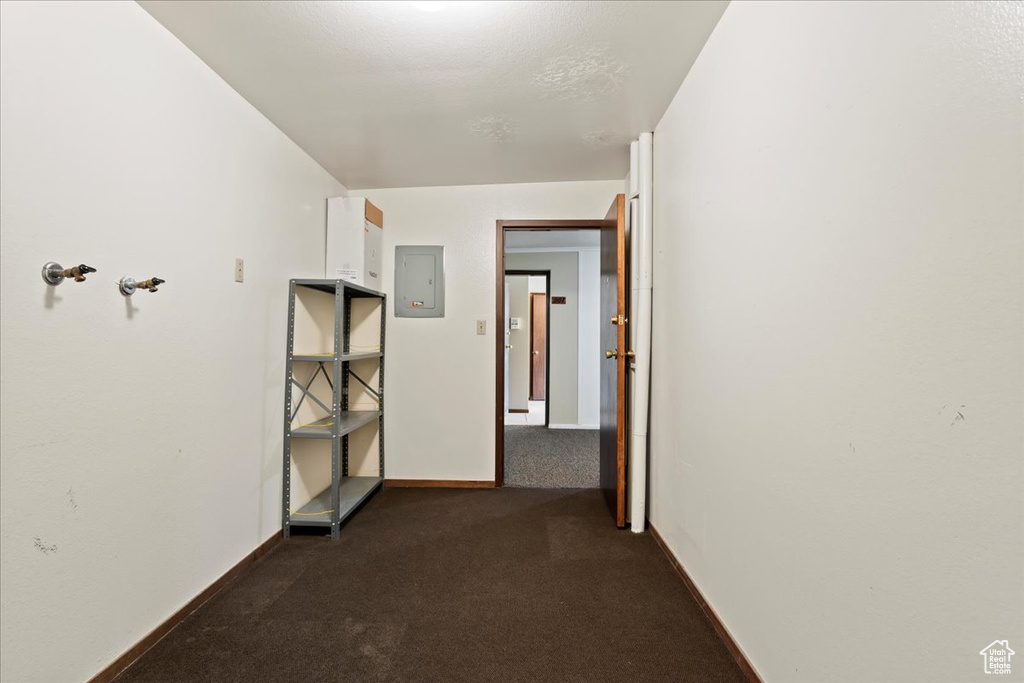 Corridor with electric panel, dark carpet, and baseboards