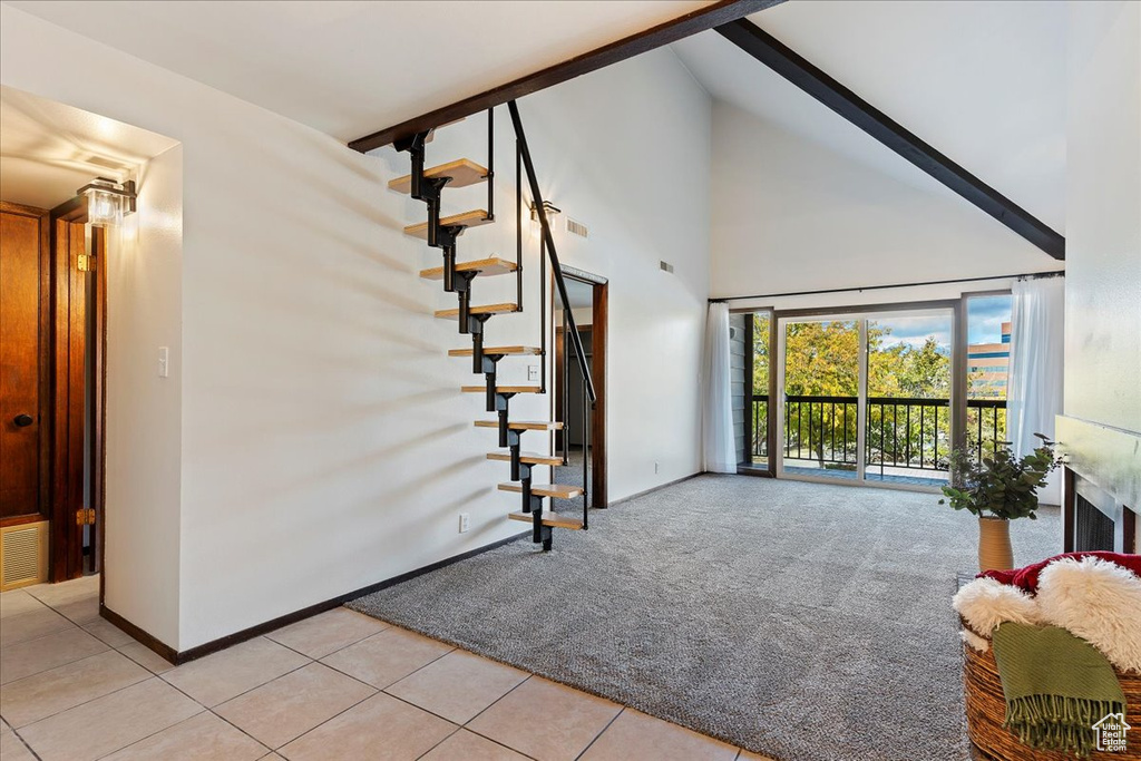 Living room with stairway, high vaulted ceiling, light carpet, light tile patterned floors, and baseboards