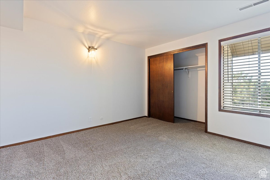 Unfurnished bedroom with carpet, a closet, and baseboards
