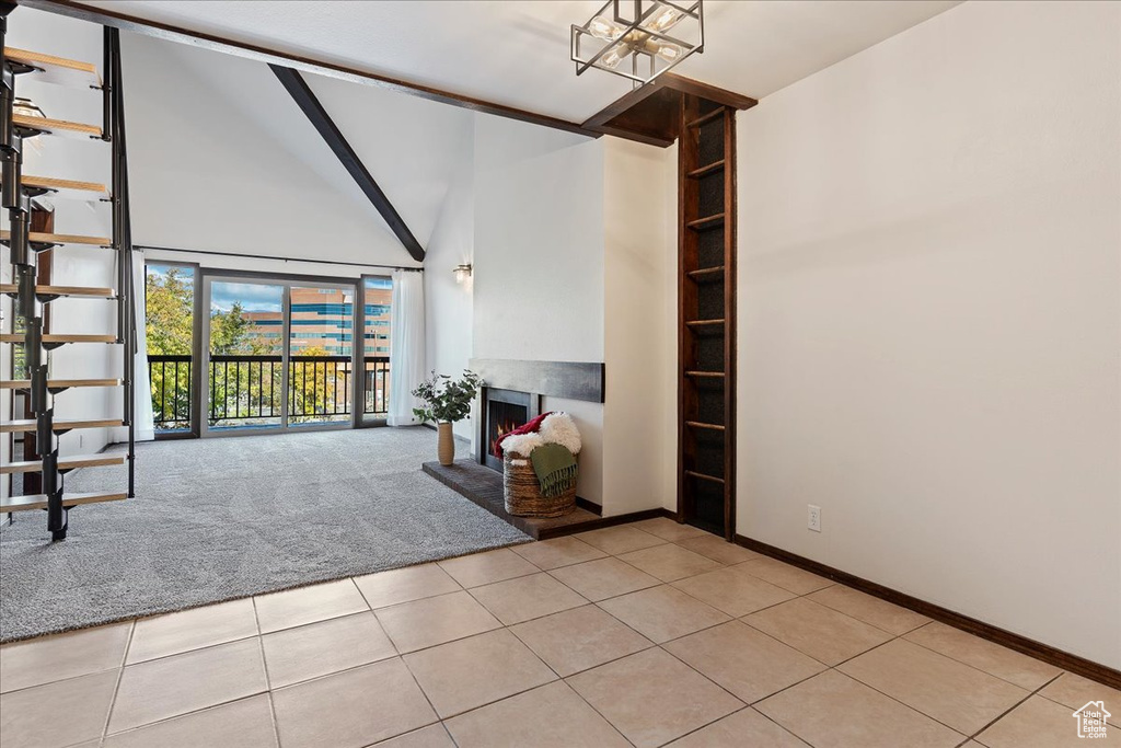 Unfurnished living room featuring baseboards, a warm lit fireplace, beamed ceiling, high vaulted ceiling, and light tile patterned floors