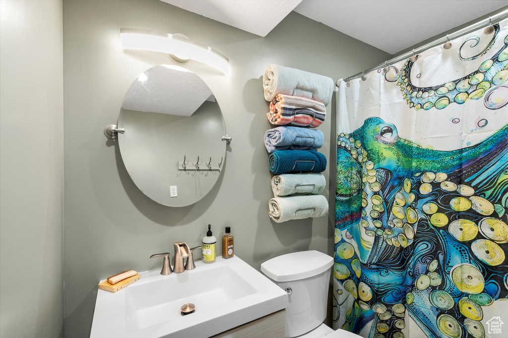 Bathroom featuring toilet, vanity, and a shower with shower curtain