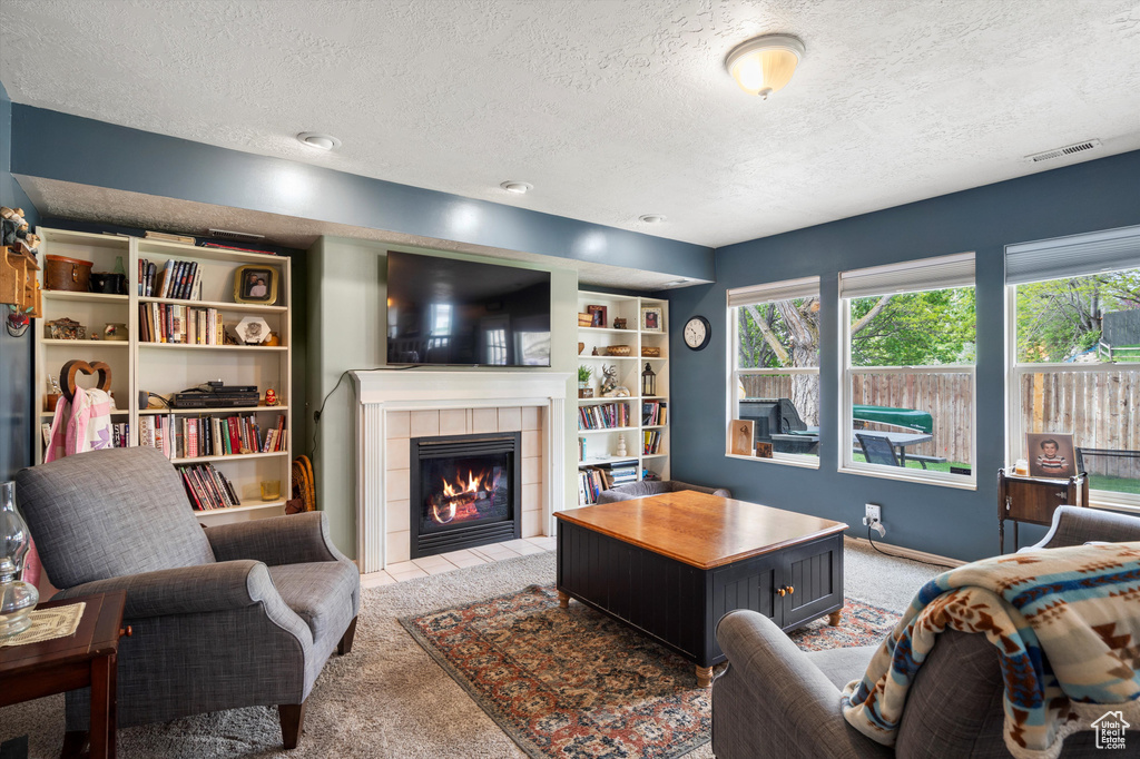 Living room with light carpet, a textured ceiling, and a tile fireplace