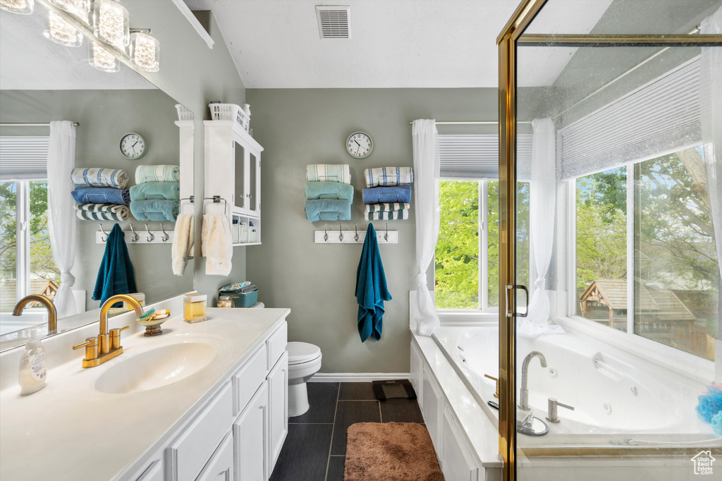 Full bathroom featuring vanity, a jetted tub, toilet, tile patterned flooring, and baseboards