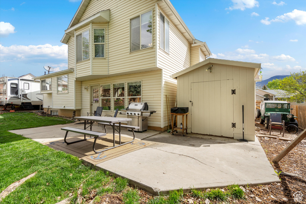 Rear view of house featuring a patio area, a yard, a shed, an outdoor structure, and a mountain view