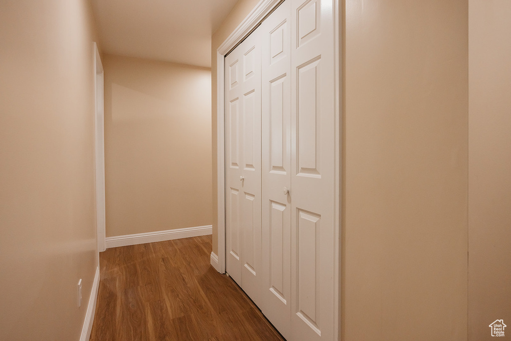 Hallway with baseboards and dark wood-type flooring
