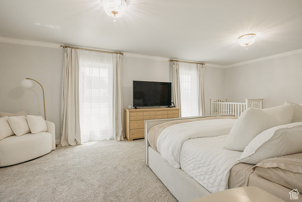 Bedroom with ornamental molding and light colored carpet