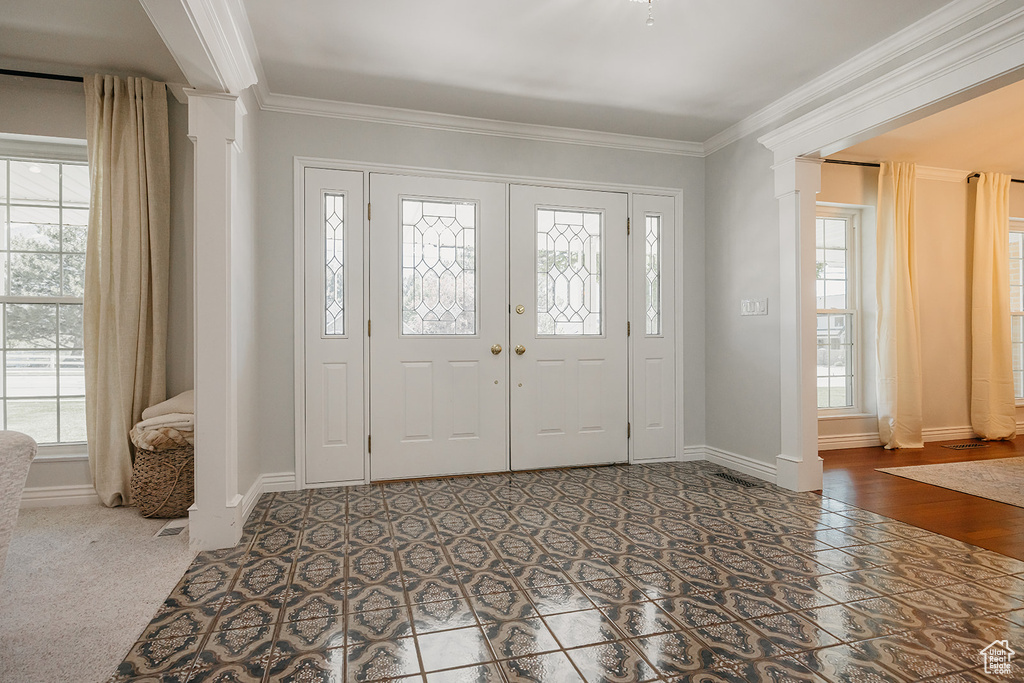 Foyer featuring ornamental molding, plenty of natural light, and decorative columns
