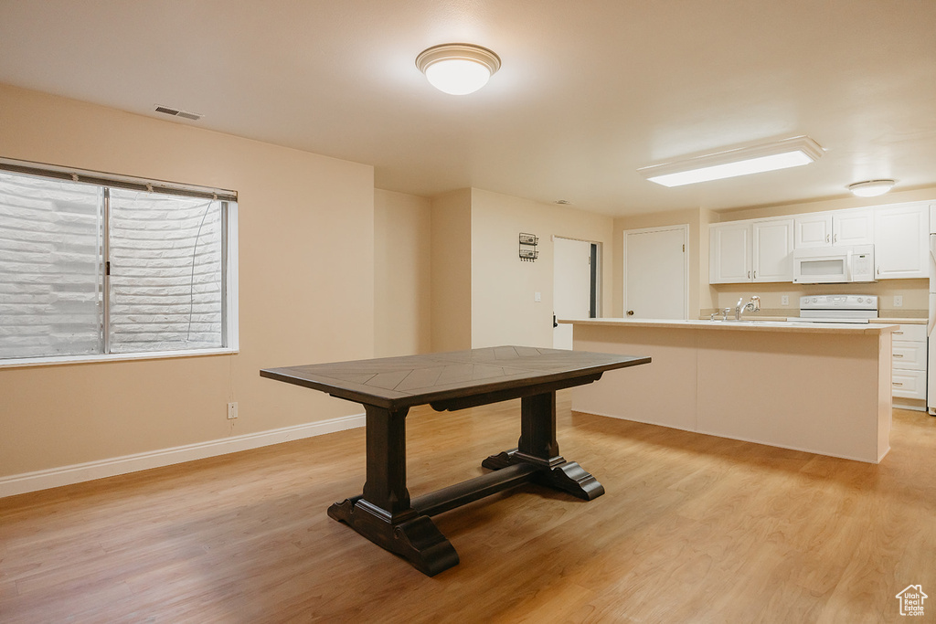 Unfurnished dining area with light wood finished floors, visible vents, baseboards, and a sink