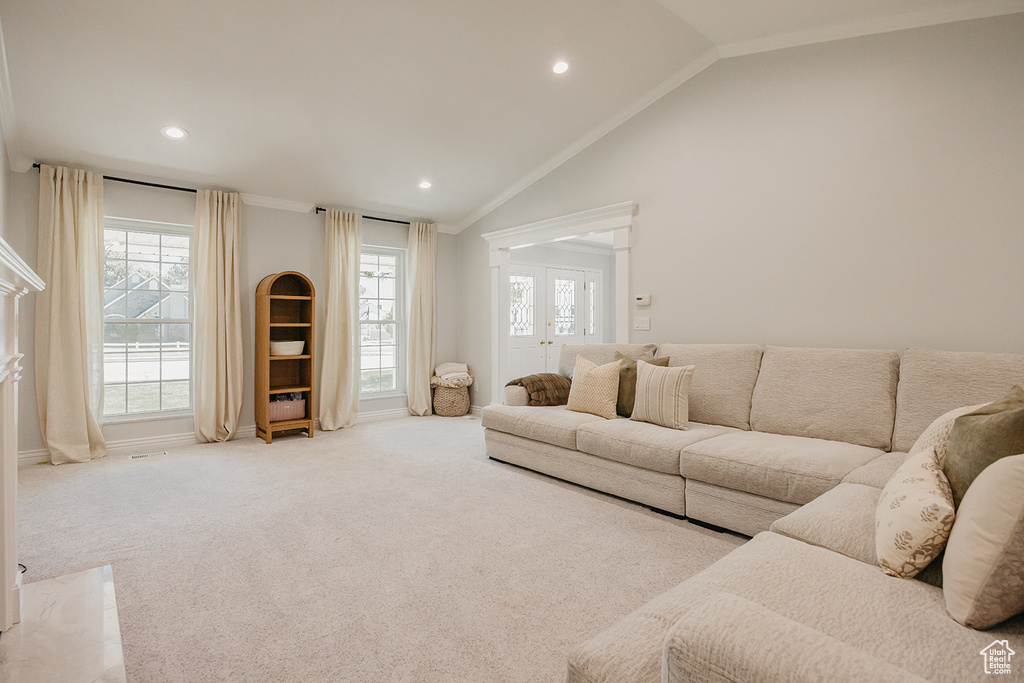 Carpeted living area with lofted ceiling, a wealth of natural light, ornamental molding, and recessed lighting
