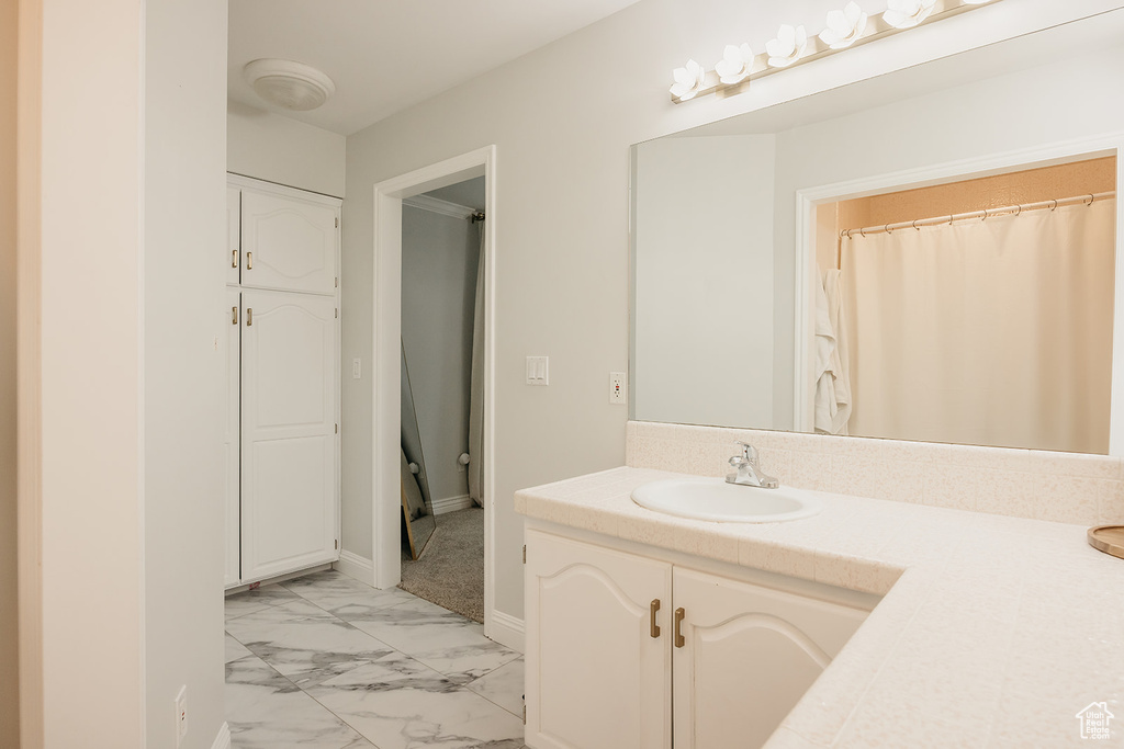 Full bath with vanity, baseboards, and marble finish floor